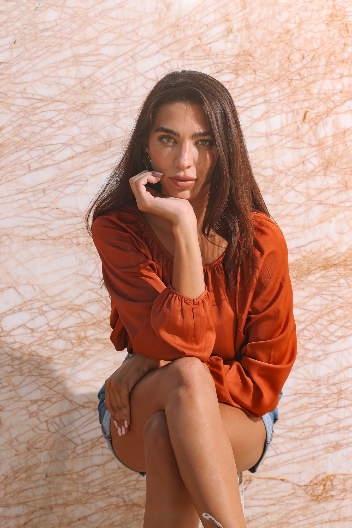 Editorial portrait in a rust blouse against gold-veined white marble at the Zein Group yard