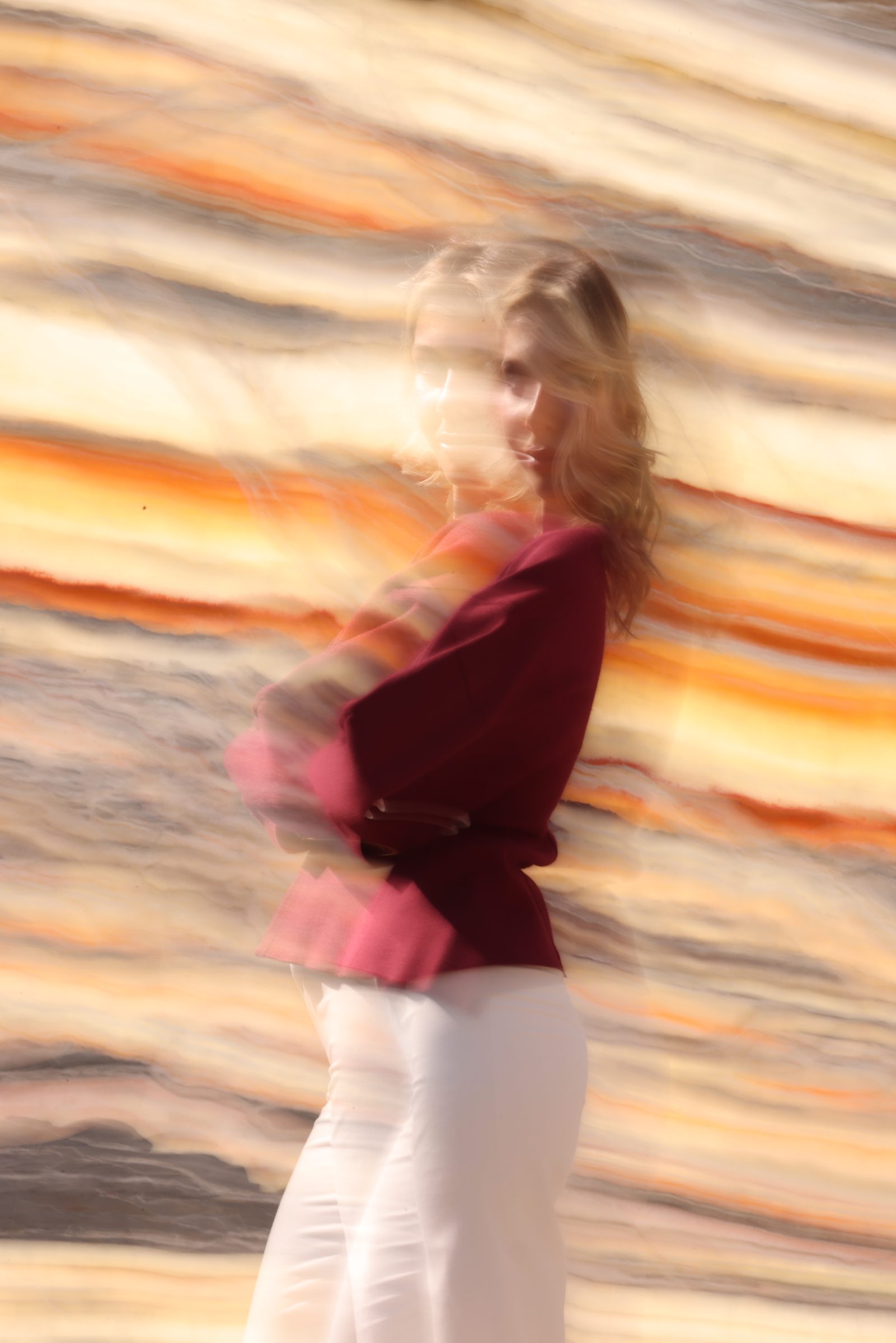 Figure in burgundy moving past streaking golden onyx — still from the Zein Group film