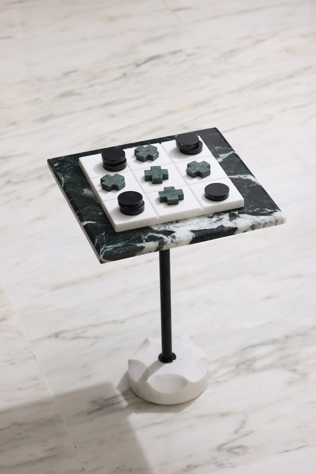Green marble game table with black stone pieces on a white marble top