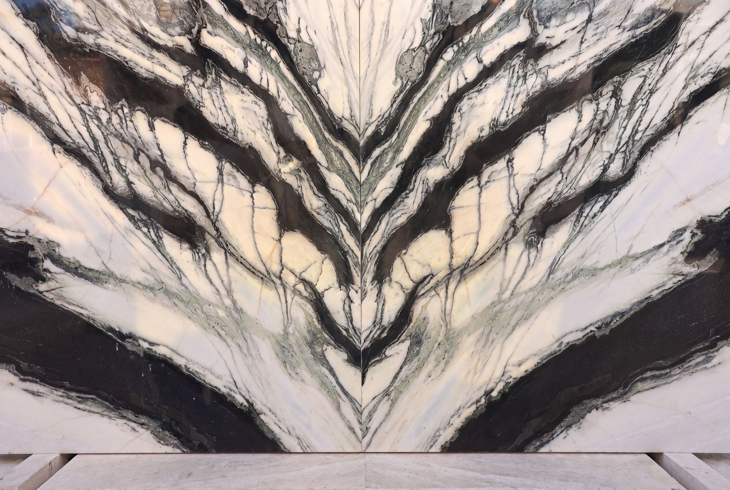 A dramatic book-matched marble slab at Zein Group — mirror-cut so its dark veins open symmetrically like wings